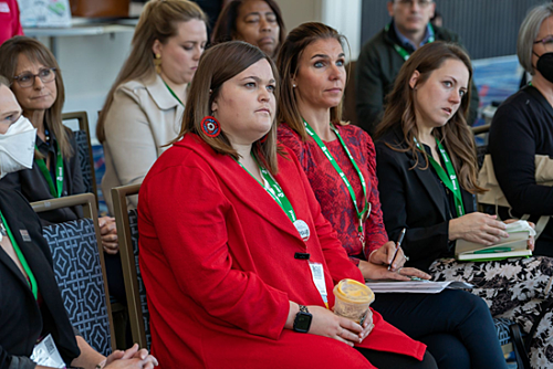 A diverse small group of mostly women seated in chairs at a conference session. They are facing the presenter who is off-camera.