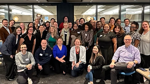 A diverse group of approximately 30 educators posing together looking at the camera.