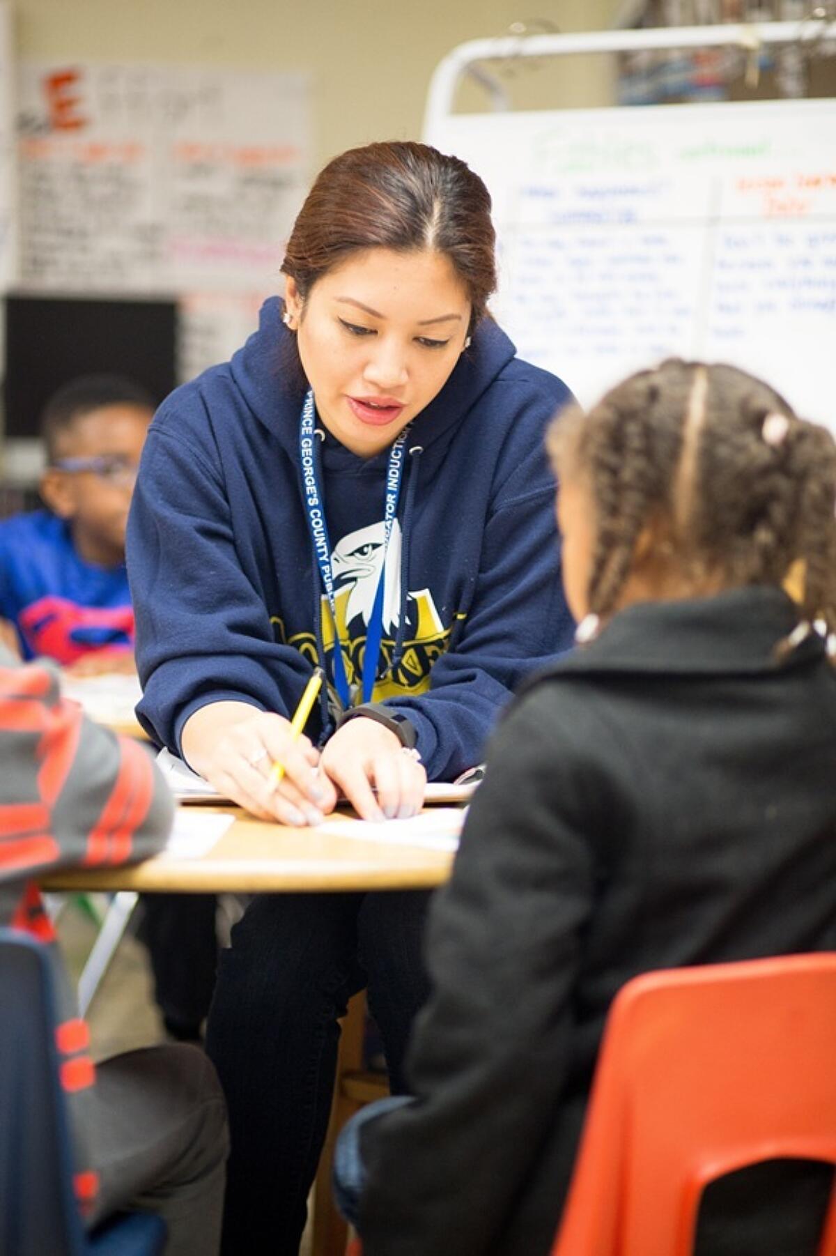 A teacher assisting a student with her work in a classroom.