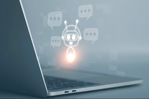 A closeup of a laptop viewed from the side, with an overlayed graphic of a chatbot robot with speech bubbles next to it.