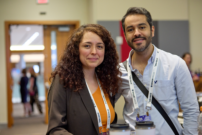 A man and woman of undetermined ethnicity standing together and smiling into the camera.