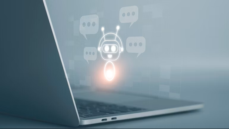 A closeup of a laptop viewed from the side, with an overlayed graphic of a chatbot robot with speech bubbles next to it.